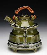 a green ornamental tea pot with a tan leather handle