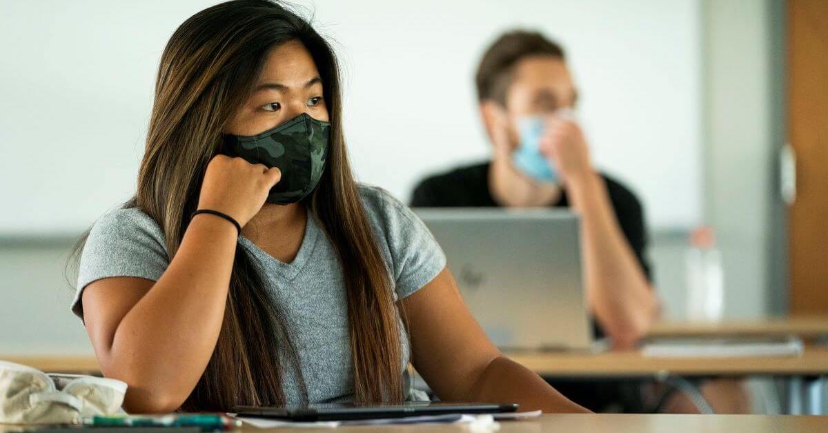 Students wearing masks sit apart in classroom as required by COVID-19 rules.