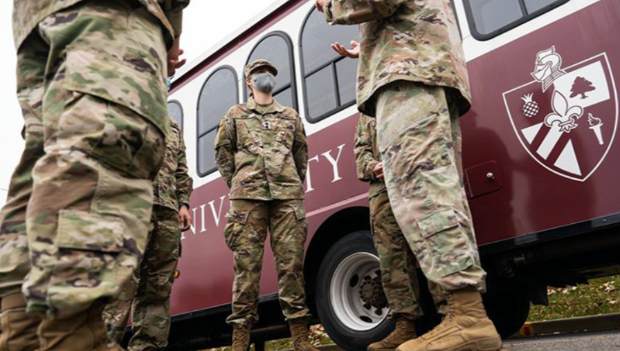 Bellarmine Military graduates standing outside in front of the ferry bus