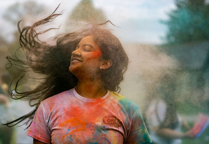 student is covered in colored dust at the Holi Festival