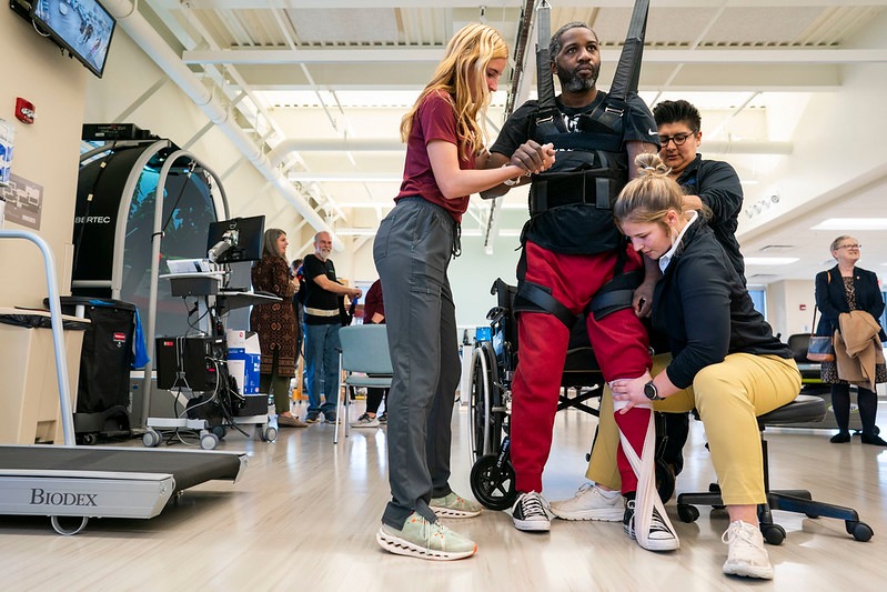 Physical therapy students work with a patient in mobility gear