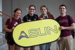 Students holding an ASUN Conference banner celebrate at the Bellarmine DI announcement