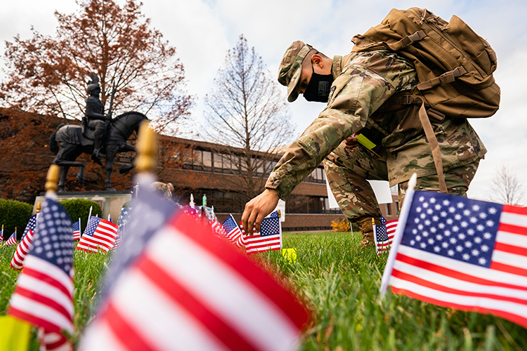 Uniformed student putting small American flag in the ground