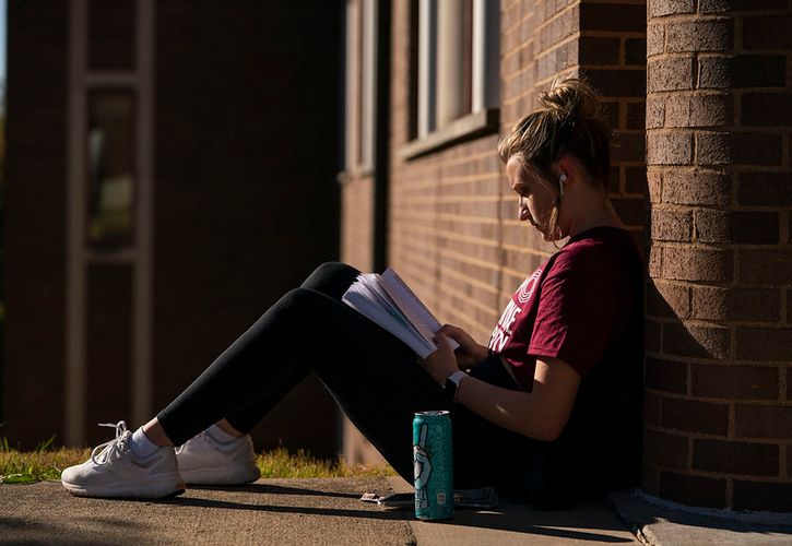 Bellarmine student studies outside on the sidewalk.