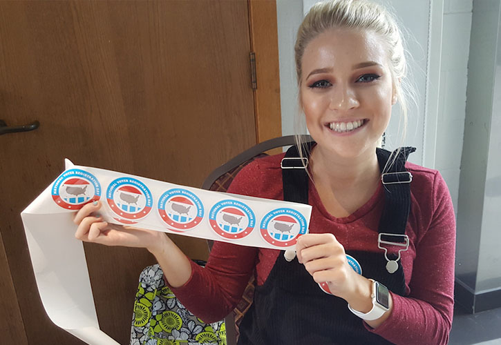 A student handing out 'I Voted' stickers