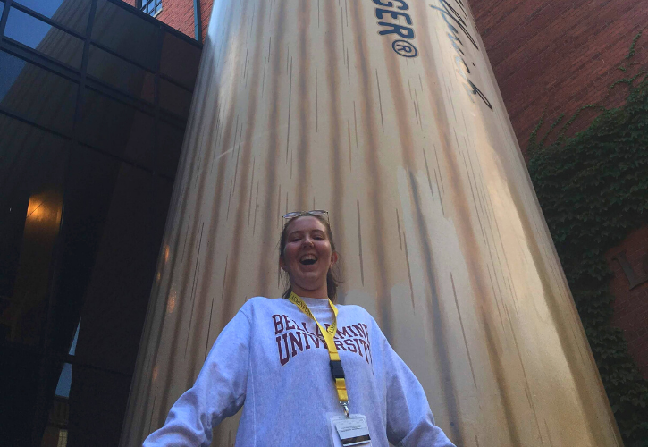 Abby Couch stands in front of a giant Louisville Slugger baseball bat