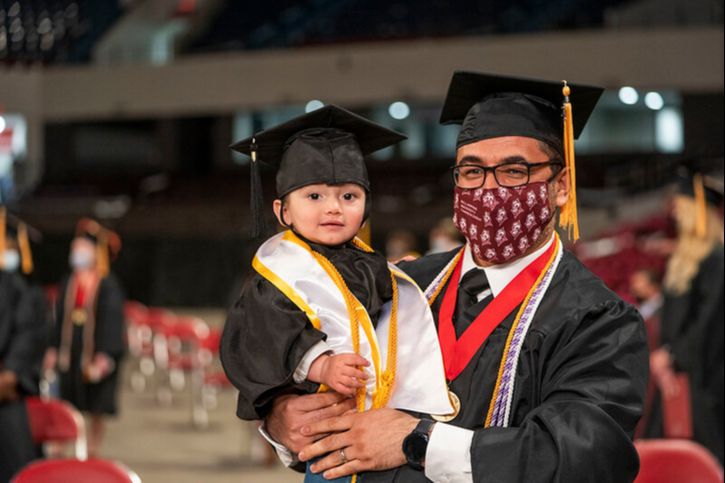 A graduate holding a child
