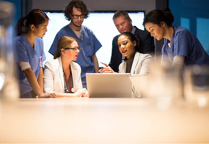 Doctors and nurses talking in front of a lap top