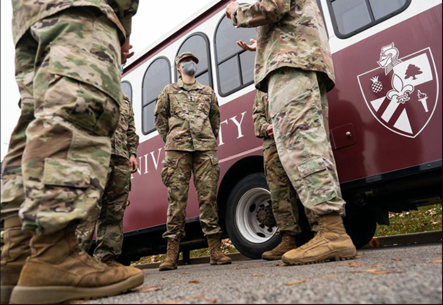 Bellarmine Military graduates standing outside in front of the ferry bus