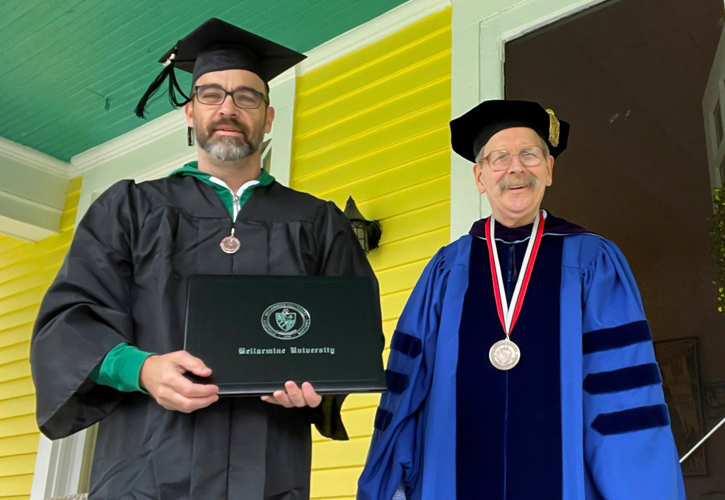 Josh Fischer and Dr. John Gatton, in full academic regalia, pose with Fischer's diploma.