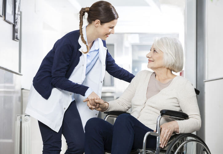 A young woman assists an older woman in a wheelchair. 