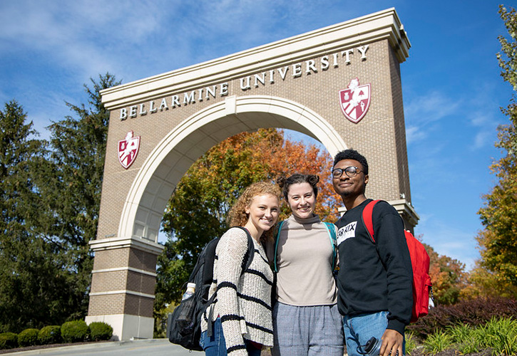 Three students in front of St. Robert's Arch