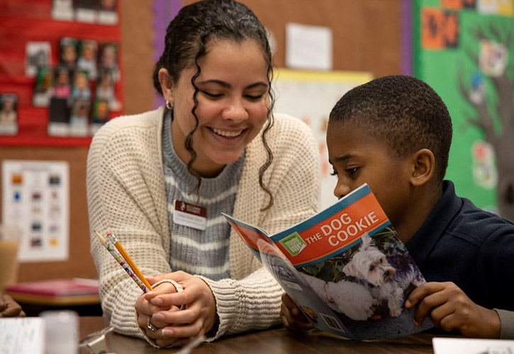 A teacher helping a young boy read
