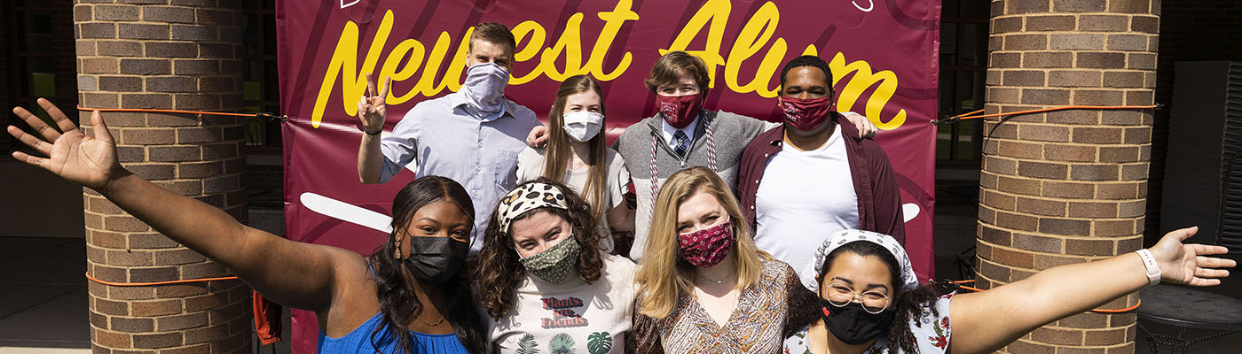 Students in front of banner that says Bellarmine's Newest Alum