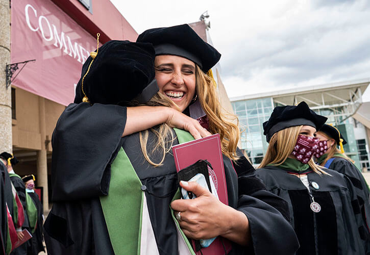Graduates hugging at commencement