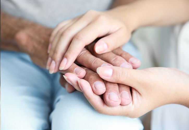 Young hands clasping old hands