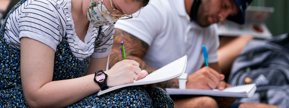 students with pens and notebooks take notes