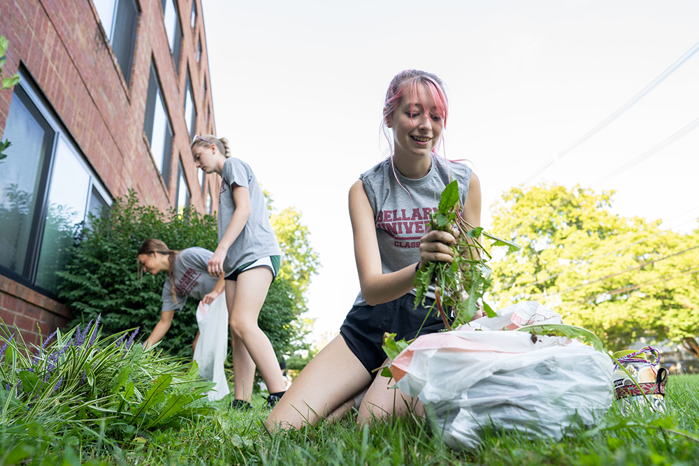 A student pulls weeds during Knights in Action 2022 community engagement event