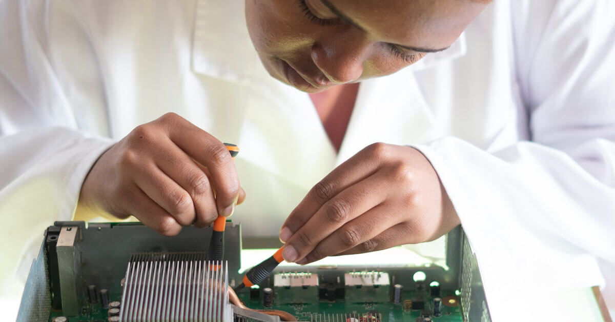 Computer scientist works on repairing a motherboard. Photo courtesy of Pexels