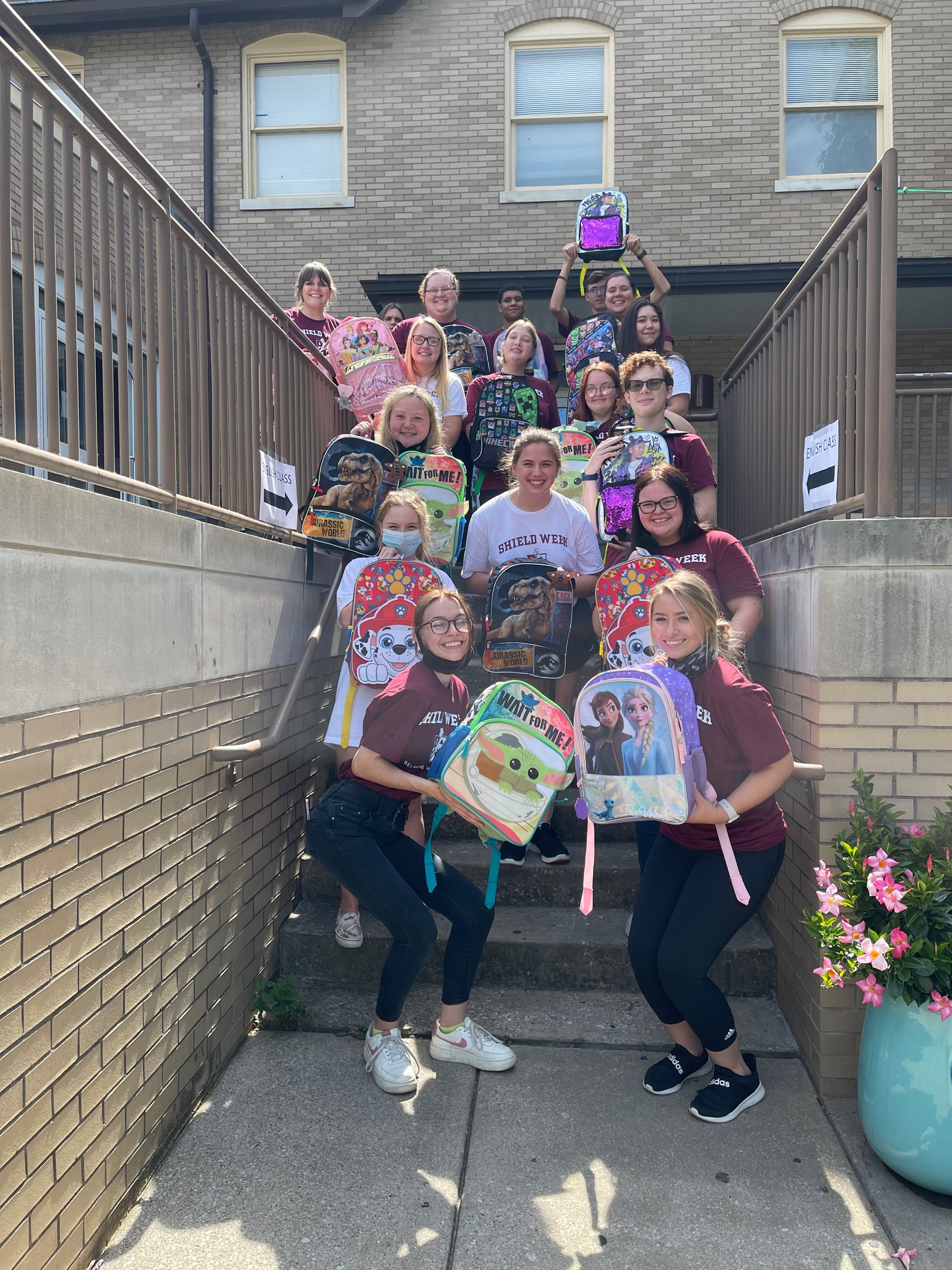 Students pose with backpacks they filled during SHIELD Week's community engagement blitz.