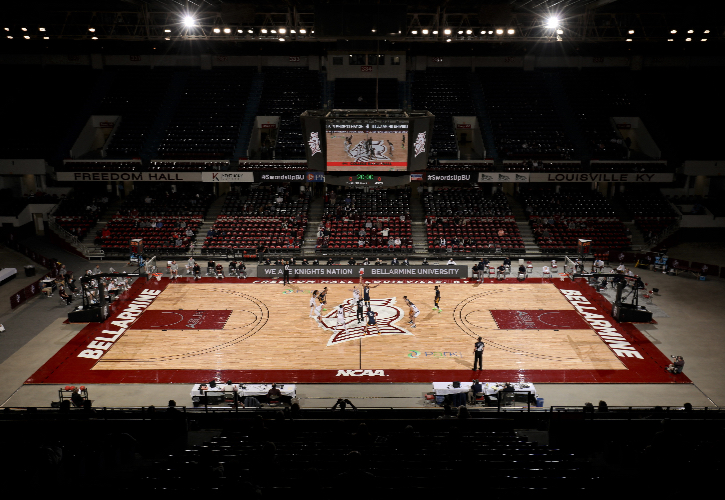 Dim basketball court, players gathered in the middle