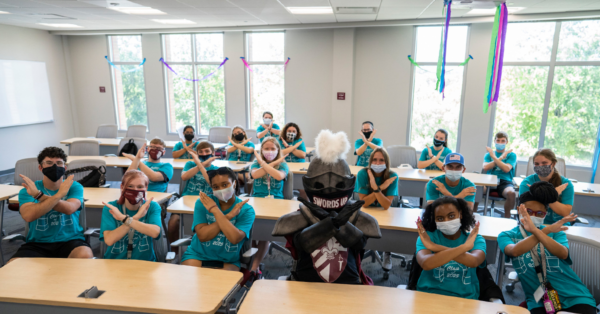 Valor, the Bellarmine mascot, and first-year students pose in a classsroom