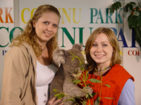 a student poses with a koala and its zookeeper