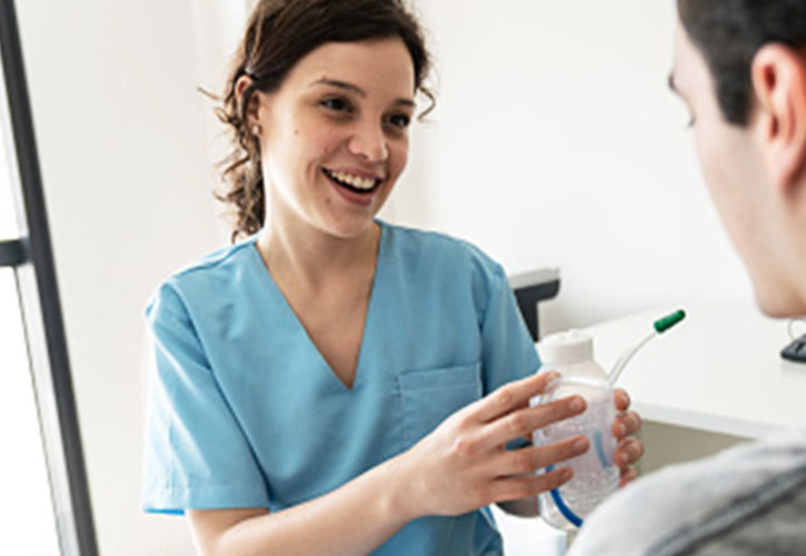 A healthcare professional showing patient how to use a respiratory device.