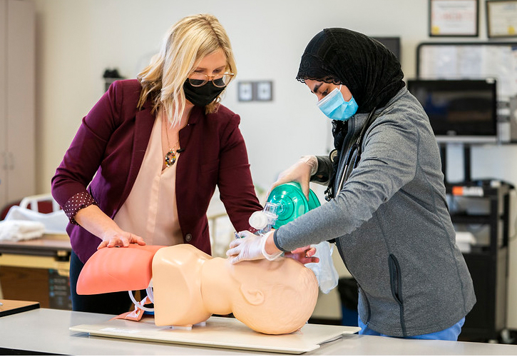 Professor and student practicing respiratory exercises on a dummy