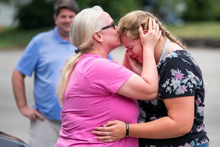 Parent kissing daughter's forehead